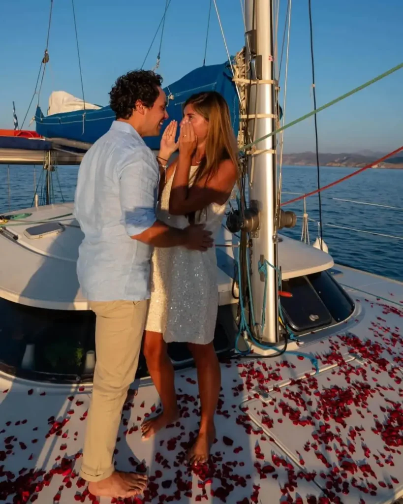 Surprise marriage proposal on a catamaran in Crete with rose petals at sunset