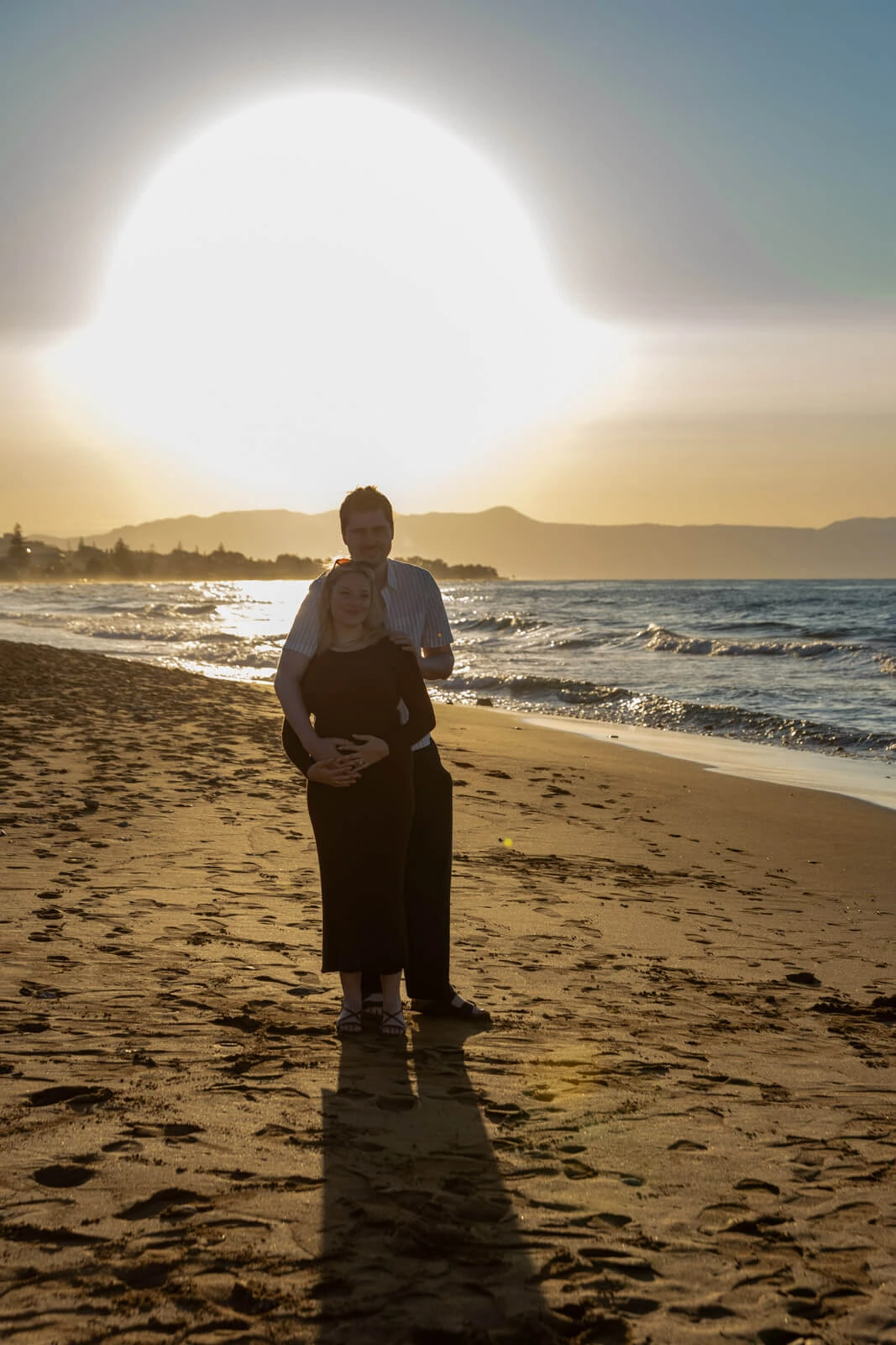 Couple standing on a beach in Crete during golden hour with sunset light proposal