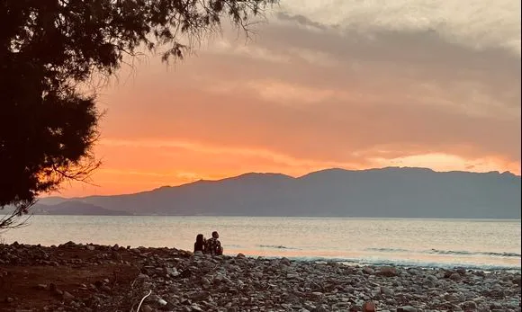 Couple watching sunset on a hidden beach in Kissamos Crete