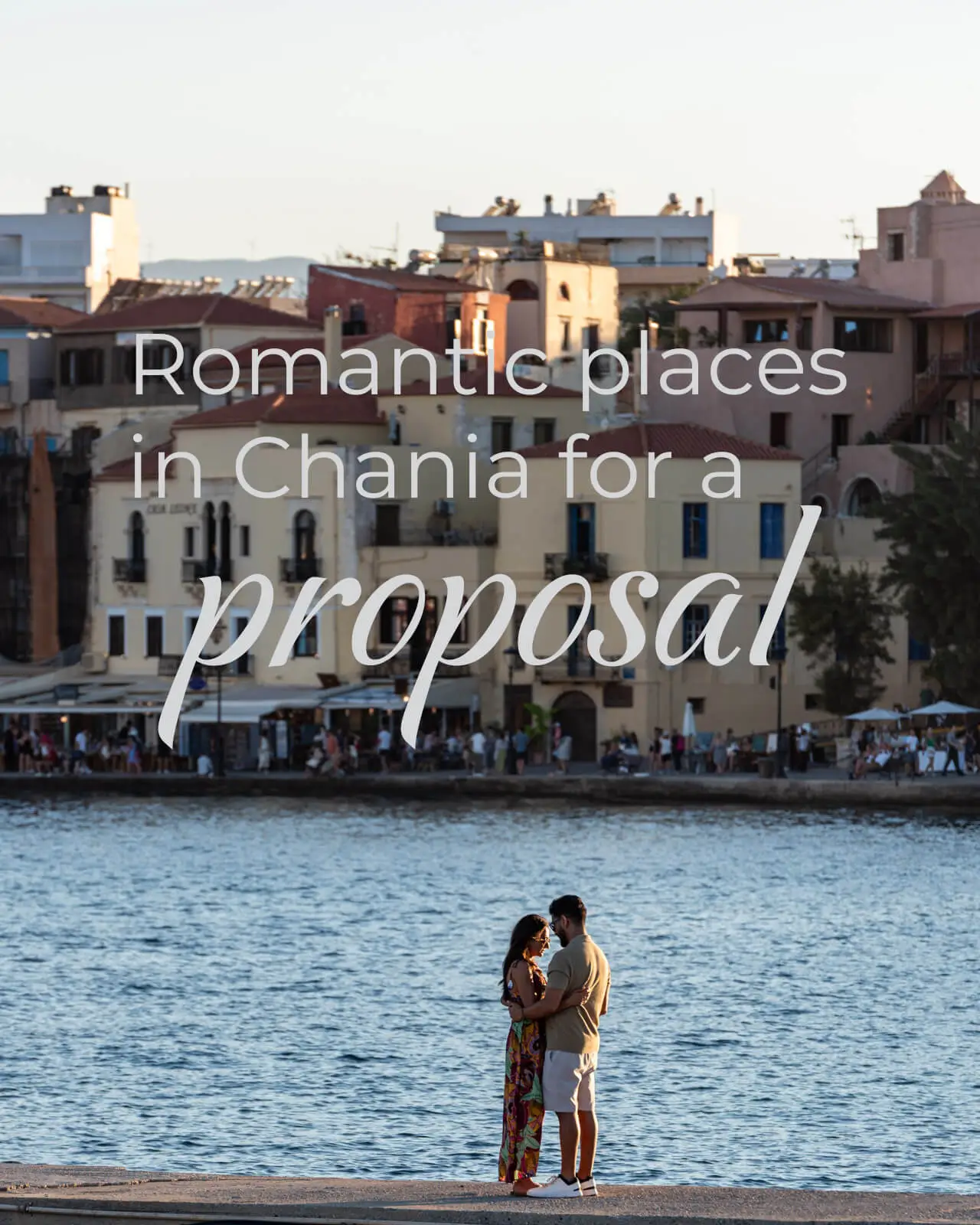 Couple sharing a romantic moment by the sea in Chania Old Harbor during sunset